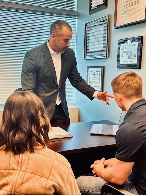 Phoenix criminal defense attorney Christian Lueders reviewing a case with two clients at the Guardian Law Group office